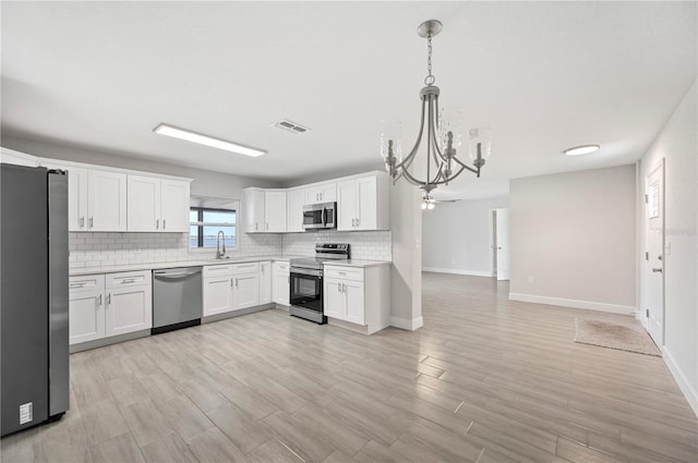 1502 Edgewater Beach Dr, Lakeland, FL 33805 - kitchen with a notable chandelier, light countertops, visible vents, decorative backsplash, and stainless steel appliances