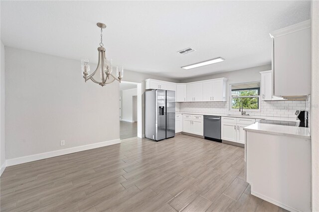 1502 Edgewater Beach Dr, Lakeland, FL 33805 - kitchen with tasteful backsplash, visible vents, an inviting chandelier, a sink, and appliances with stainless steel finishes