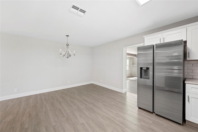 1502 Edgewater Beach Dr, Lakeland, FL 33805 - kitchen featuring light wood-style flooring, visible vents, stainless steel fridge, baseboards, and a notable chandelier