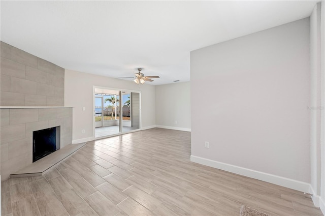 1502 Edgewater Beach Dr, Lakeland, FL 33805 - unfurnished living room featuring light wood-style flooring, ceiling fan, a fireplace, and baseboards