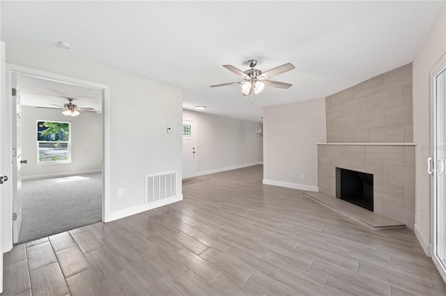 1502 Edgewater Beach Dr, Lakeland, FL 33805 - unfurnished living room with a tiled fireplace, visible vents, ceiling fan, and light wood finished floors