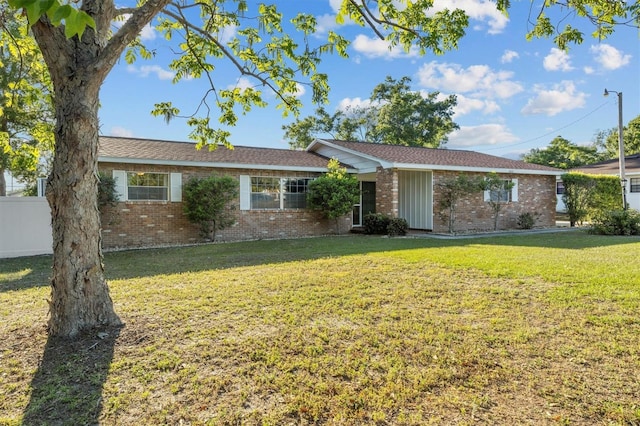 ranch-style house featuring a front yard, fence, and brick siding