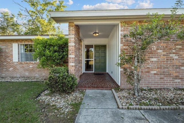 view of exterior entry featuring brick siding