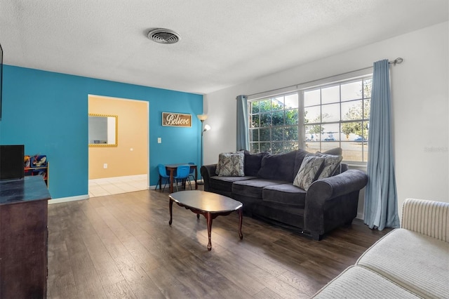 living room featuring visible vents, baseboards, wood finished floors, and a textured ceiling