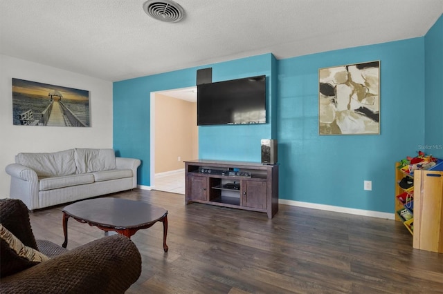 living room featuring a textured ceiling, wood finished floors, baseboards, and visible vents
