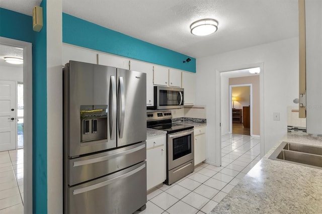 kitchen featuring a sink, light tile patterned floors, appliances with stainless steel finishes, and a textured ceiling