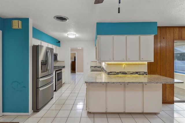 kitchen with visible vents, white cabinets, a peninsula, a textured ceiling, and stainless steel appliances
