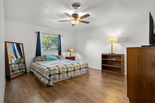 bedroom featuring visible vents, baseboards, wood finished floors, and a textured ceiling