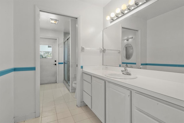 bathroom featuring tile patterned floors, toilet, a stall shower, and vanity
