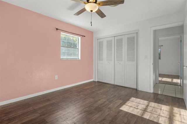 unfurnished bedroom featuring a closet, baseboards, a ceiling fan, and dark wood-style floors