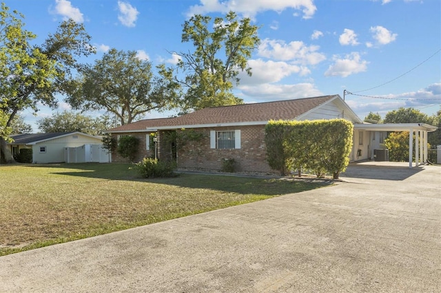 view of front of home featuring a carport, driveway, a front yard, brick siding, and central AC