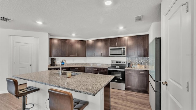 613 Sarner Pass Way, Winter Haven, FL 33881 - kitchen with stainless steel appliances, light wood-style flooring, a breakfast bar, recessed lighting, and a textured ceiling