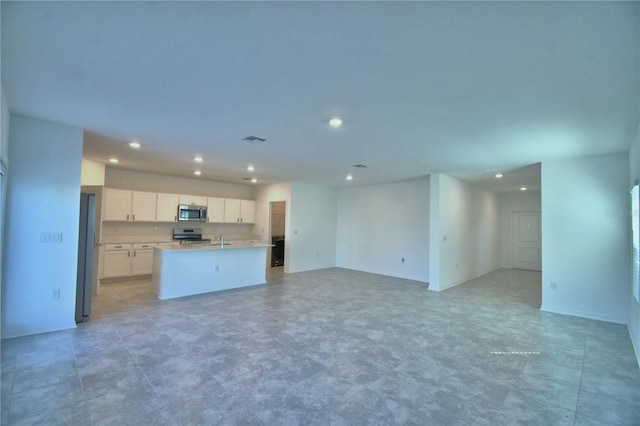 unfurnished living room featuring baseboards, visible vents, and recessed lighting