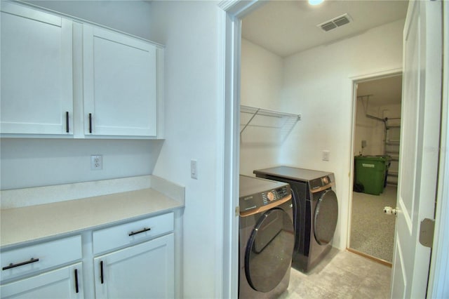 laundry area featuring washer and dryer, cabinet space, and visible vents