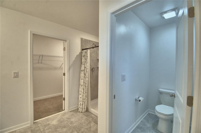 bathroom featuring a shower stall, toilet, a walk in closet, and tile patterned floors