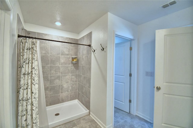 full bath featuring baseboards, visible vents, tile patterned flooring, and tiled shower