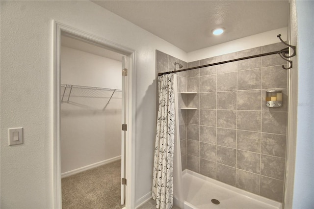full bath with baseboards, a spacious closet, and a shower stall