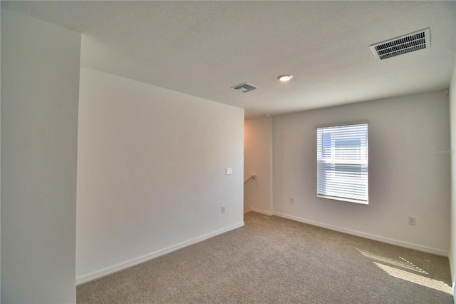 carpeted empty room featuring baseboards and visible vents