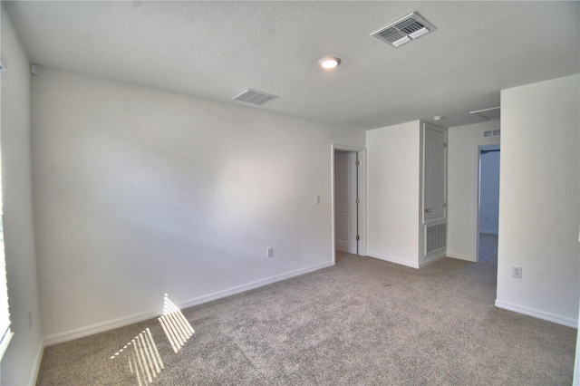 carpeted empty room featuring baseboards, a textured ceiling, and visible vents