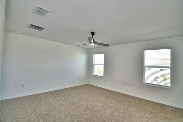 empty room featuring visible vents, carpet floors, and ceiling fan