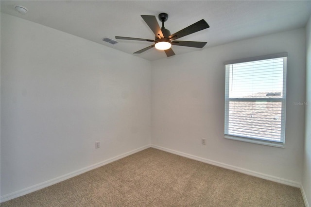 carpeted empty room with visible vents, baseboards, and ceiling fan