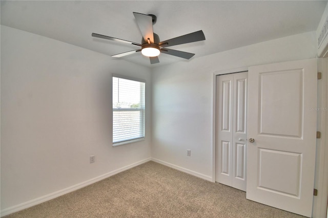 unfurnished bedroom featuring a closet, a ceiling fan, baseboards, and light carpet