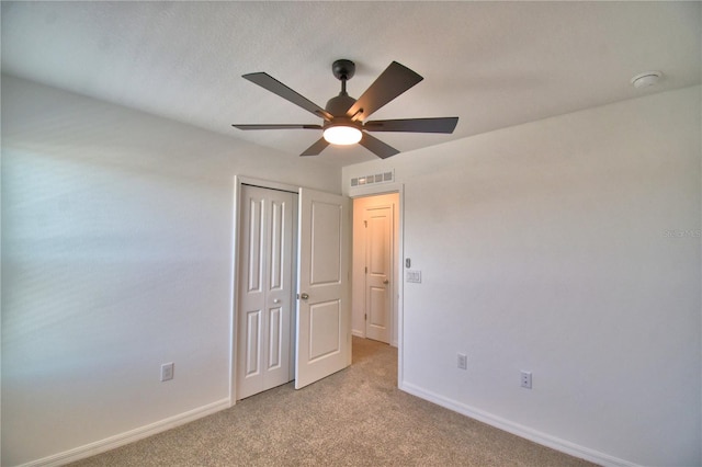 unfurnished bedroom featuring visible vents, light carpet, a closet, baseboards, and ceiling fan