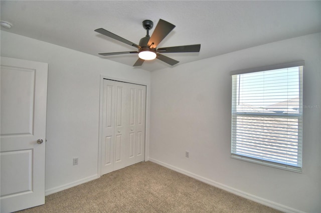 unfurnished bedroom featuring light colored carpet, baseboards, multiple windows, and a closet