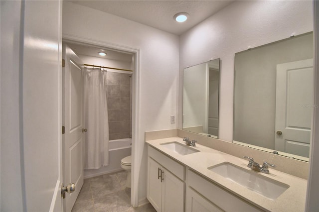 full bathroom featuring double vanity, tile patterned flooring, toilet, and a sink