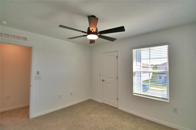 spare room featuring baseboards, visible vents, light colored carpet, and ceiling fan