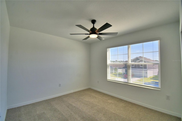 spare room featuring baseboards, a ceiling fan, and light carpet