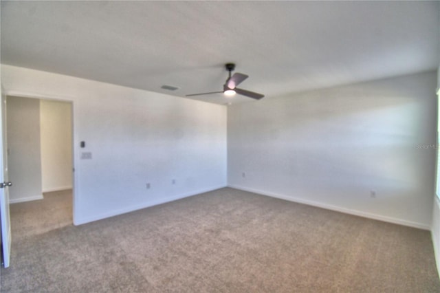 carpeted empty room featuring visible vents, a ceiling fan, and baseboards