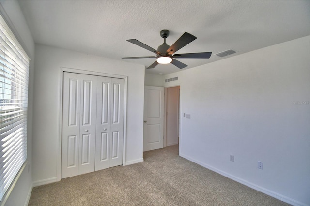 unfurnished bedroom with a closet, visible vents, carpet flooring, and multiple windows