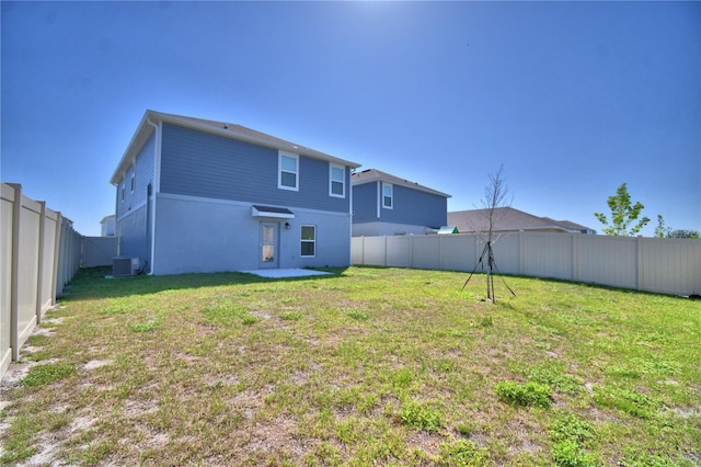 rear view of house with central AC, a fenced backyard, and a lawn