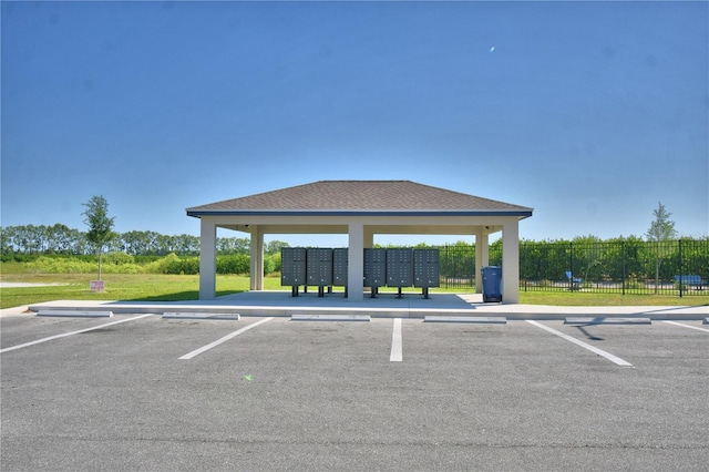 uncovered parking lot featuring fence and mail area