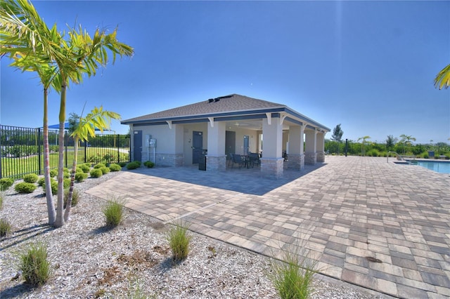 back of house featuring a community pool, a patio, stucco siding, and fence