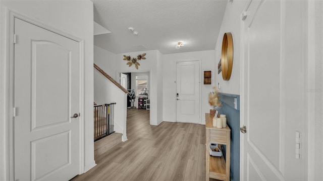 entrance foyer with baseboards, a textured ceiling, light wood-style floors, and stairway