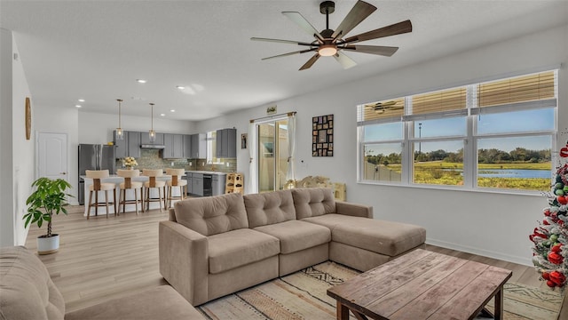 living room with baseboards, a ceiling fan, light wood-style floors, and recessed lighting