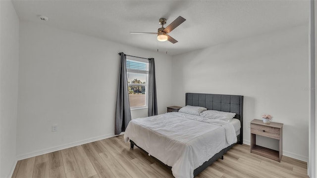 bedroom with light wood-style floors, a ceiling fan, and baseboards