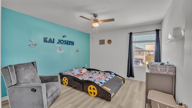 bedroom featuring baseboards, a ceiling fan, wood finished floors, and a textured ceiling