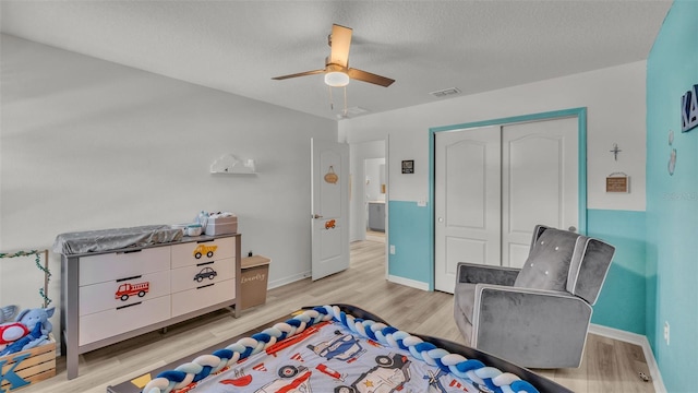 bedroom featuring light wood finished floors, visible vents, a closet, and ceiling fan