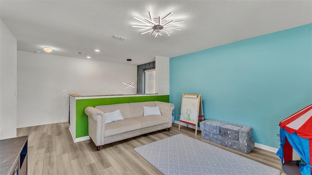 living room with baseboards, wood finished floors, visible vents, and a textured ceiling