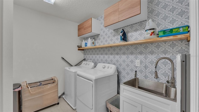 washroom with light tile patterned floors, washing machine and dryer, a sink, cabinet space, and a textured ceiling