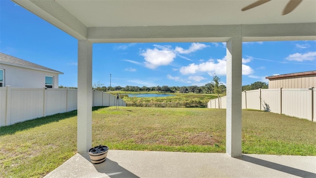 view of yard featuring a patio area, a fenced backyard, a ceiling fan, and a water view