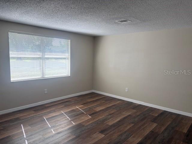 4830 Melody Ln, Lakeland, FL 33805 - unfurnished room with visible vents, dark wood-style flooring, baseboards, and a textured ceiling