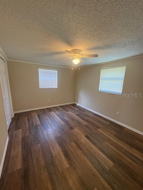 4830 Melody Ln, Lakeland, FL 33805 - unfurnished bedroom featuring crown molding, ceiling fan, dark wood-type flooring, a textured ceiling, and baseboards
