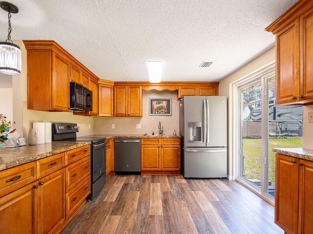 4830 Melody Ln, Lakeland, FL 33805 - kitchen featuring brown cabinetry, wood finished floors, a sink, and black appliances
