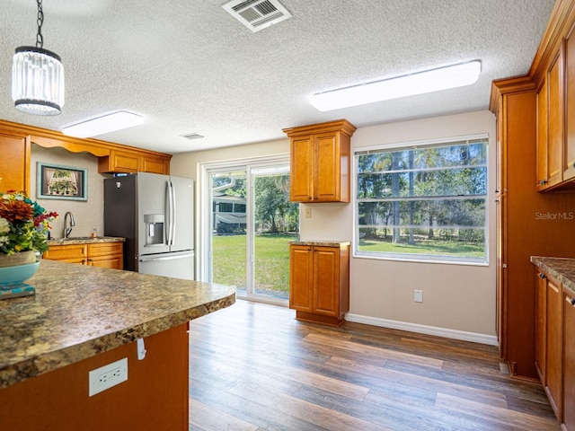 4830 Melody Ln, Lakeland, FL 33805 - kitchen featuring wood finished floors, brown cabinetry, stainless steel fridge, baseboards, and visible vents
