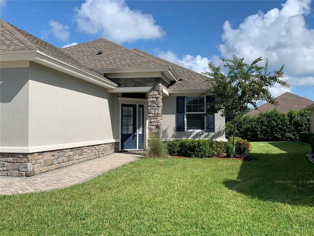 7779 Lake James Blvd, Lakeland, FL 33810 - entrance to property with stone siding, stucco siding, a yard, and a shingled roof