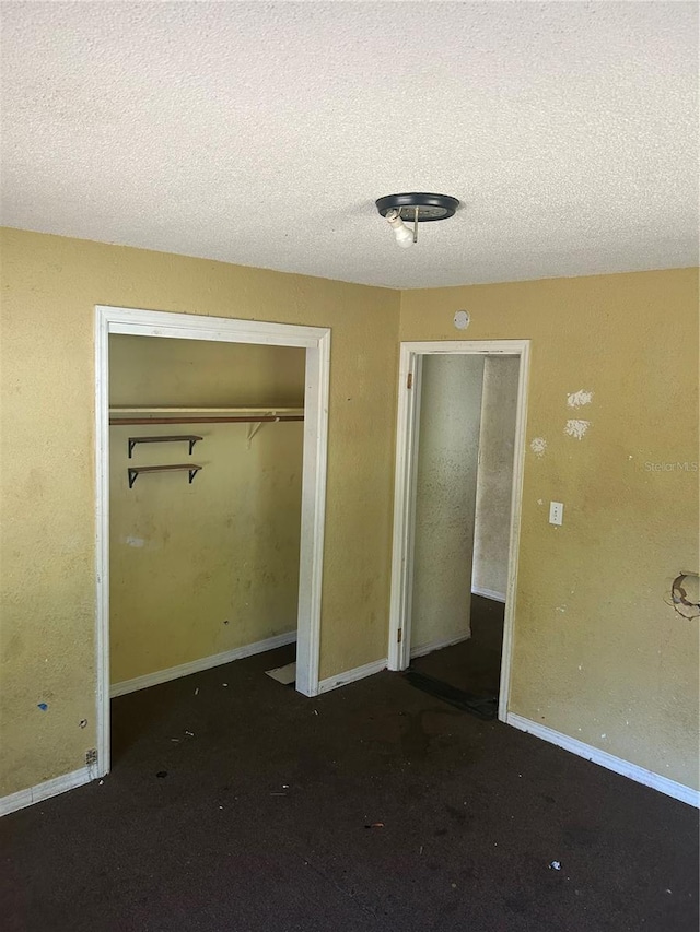 unfurnished bedroom with a textured ceiling, a closet, carpet flooring, and baseboards